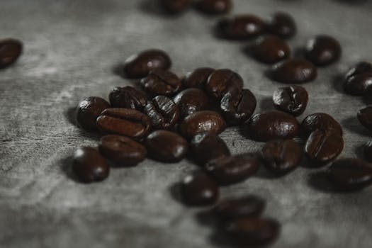 Aromatic roasted coffee beans scattered on a rustic surface in an artistic close-up shot.