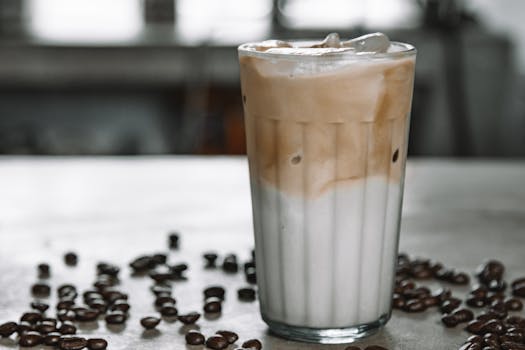 桌上咖啡豆环绕，一杯清爽的冰咖啡配着泡沫牛奶
