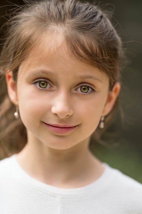 Free Adorable girl with green eyes looking at camera and smiling on summer day Stock Photo