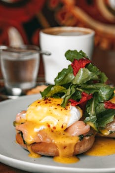 Savor a perfect brunch of eggs benedict with fresh greens and coffee.