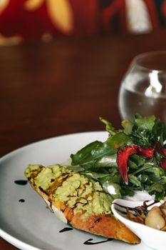 Close-up of avocado toast with a fresh salad on a plate, perfect for a healthy meal.