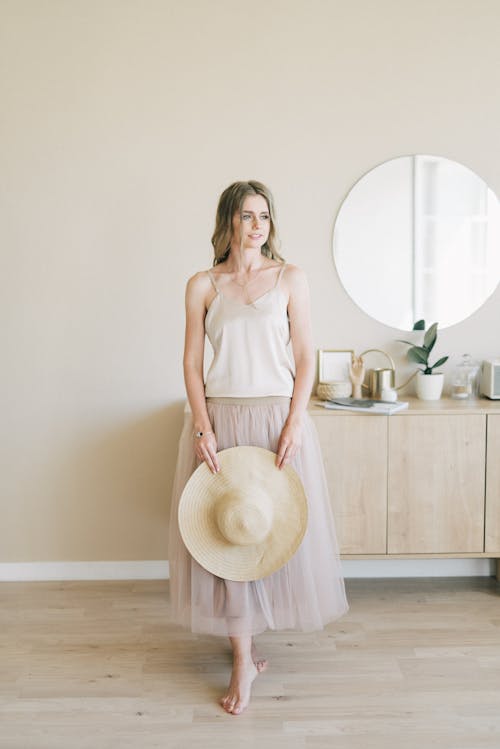 Woman In White Tank Top And Pink Skirt Standing Beside Brown Wooden Table