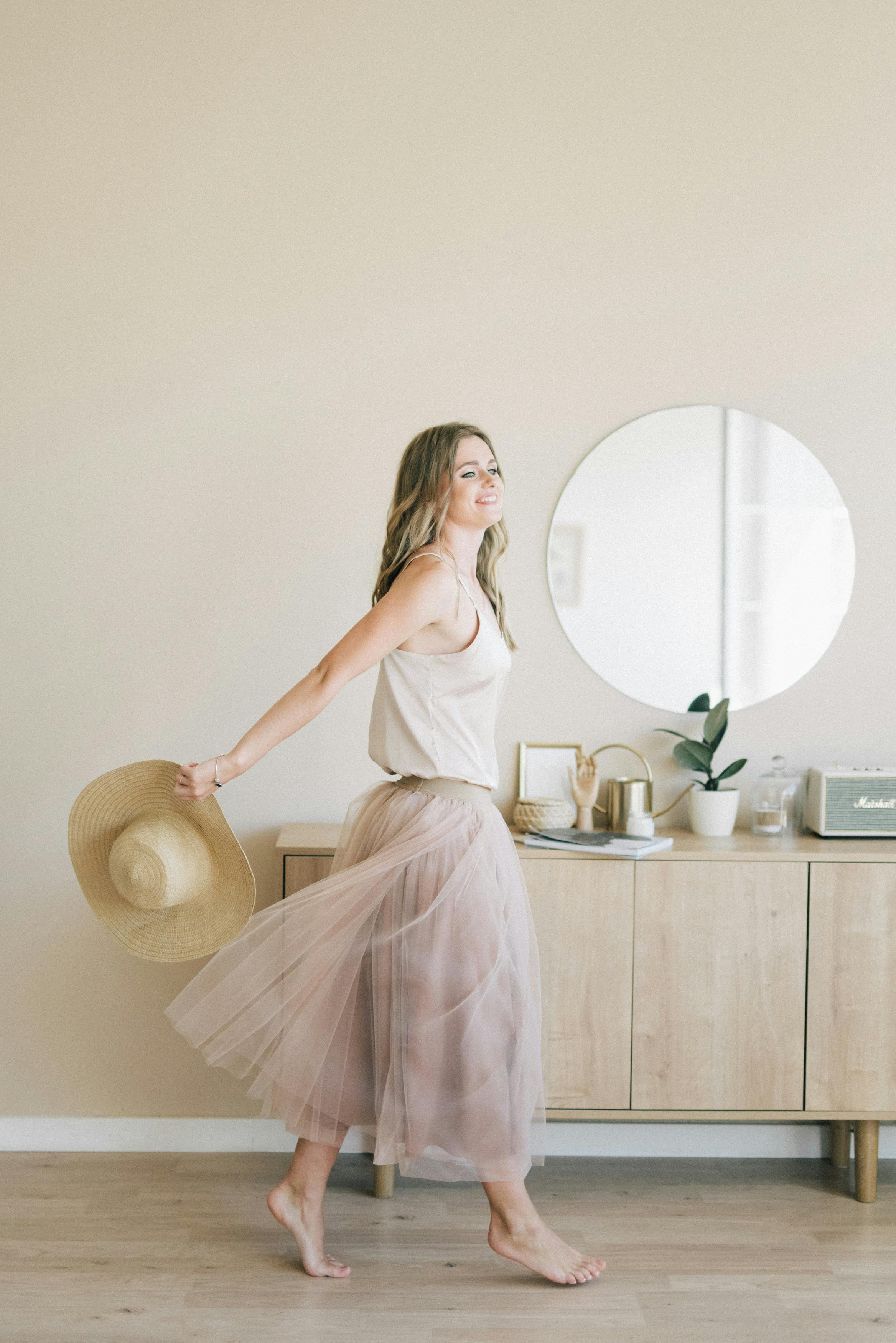 A young woman in a flowing skirt gracefully strolls indoors, epitomizing elegance and modern lifestyle.