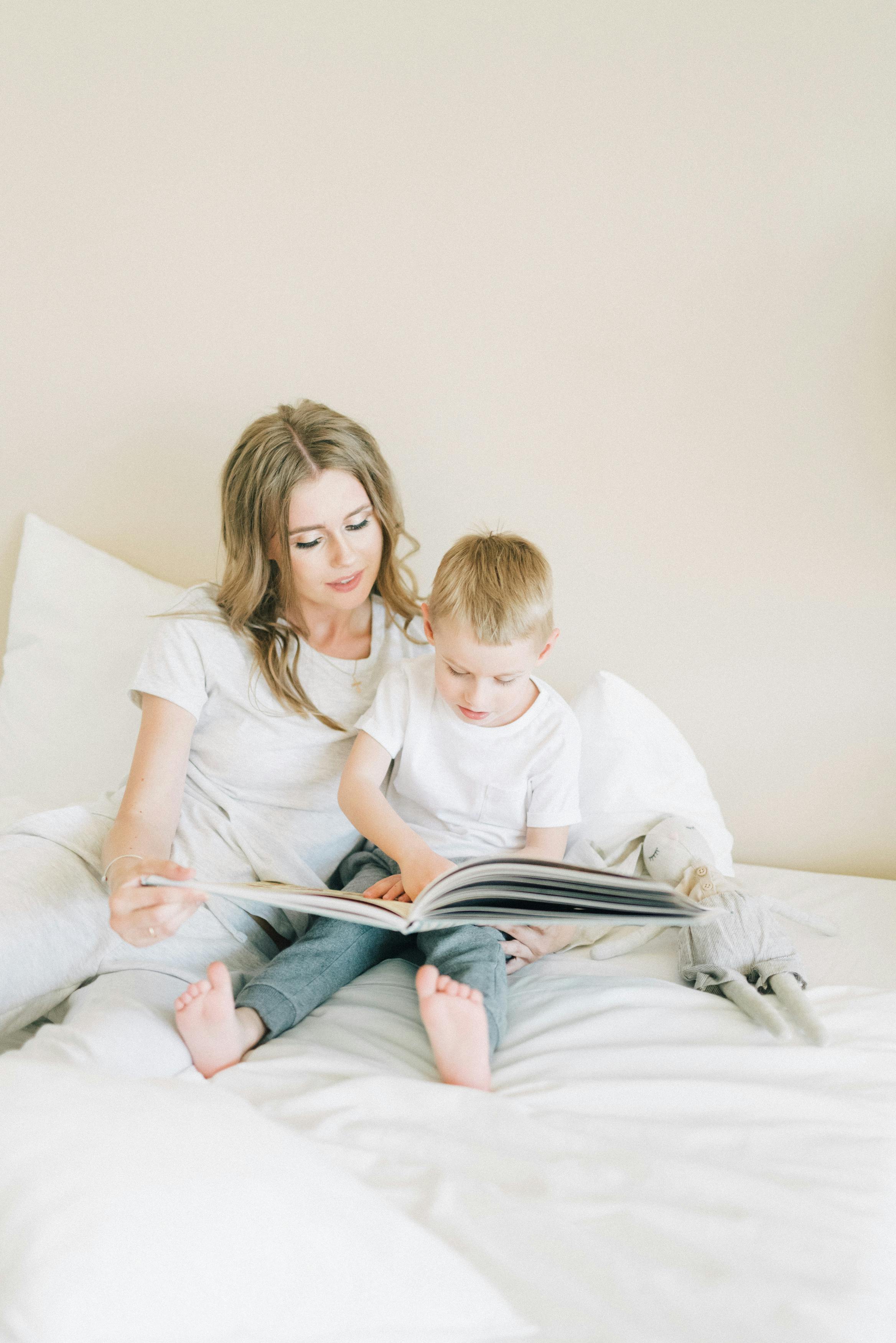 woman in white crew neck t shirt sitting beside boy in white t shirt