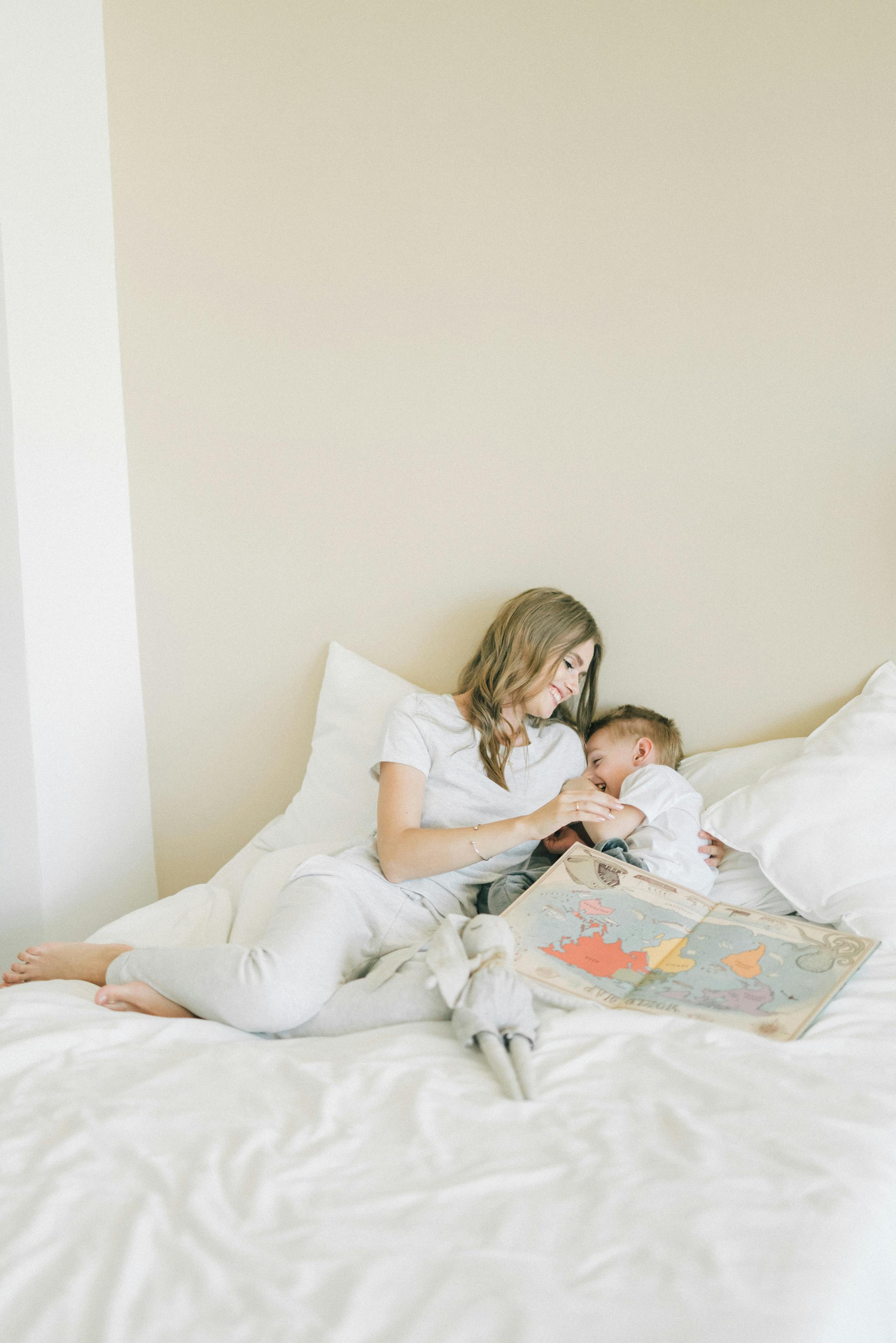 a woman playing with her son on a bed