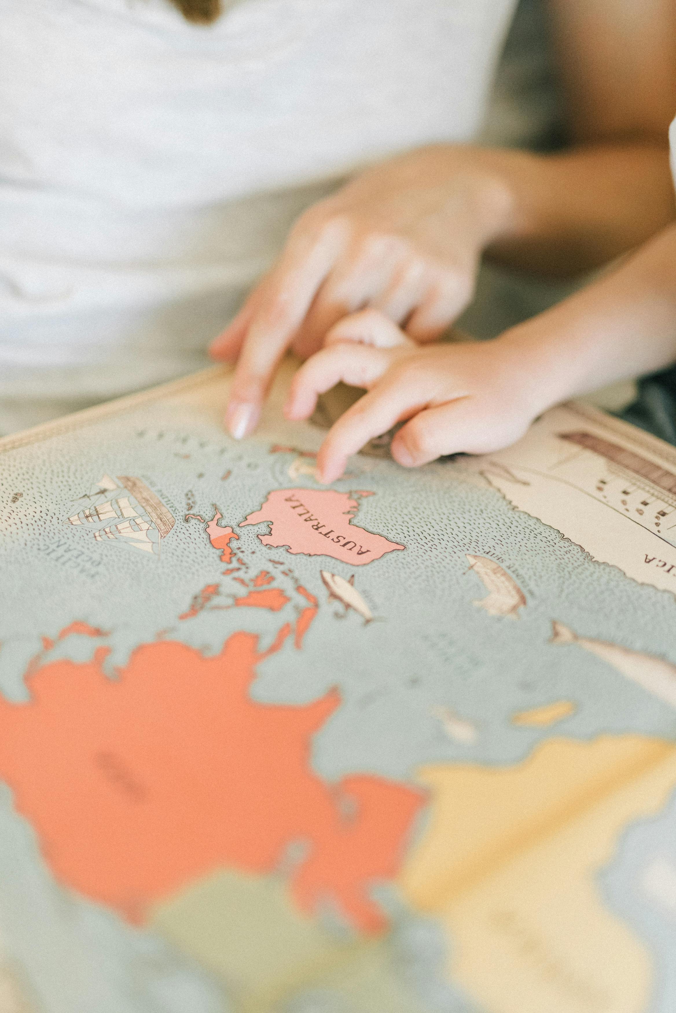 A close-up of hands pointing at a map of Australia, symbolizing exploration and learning.