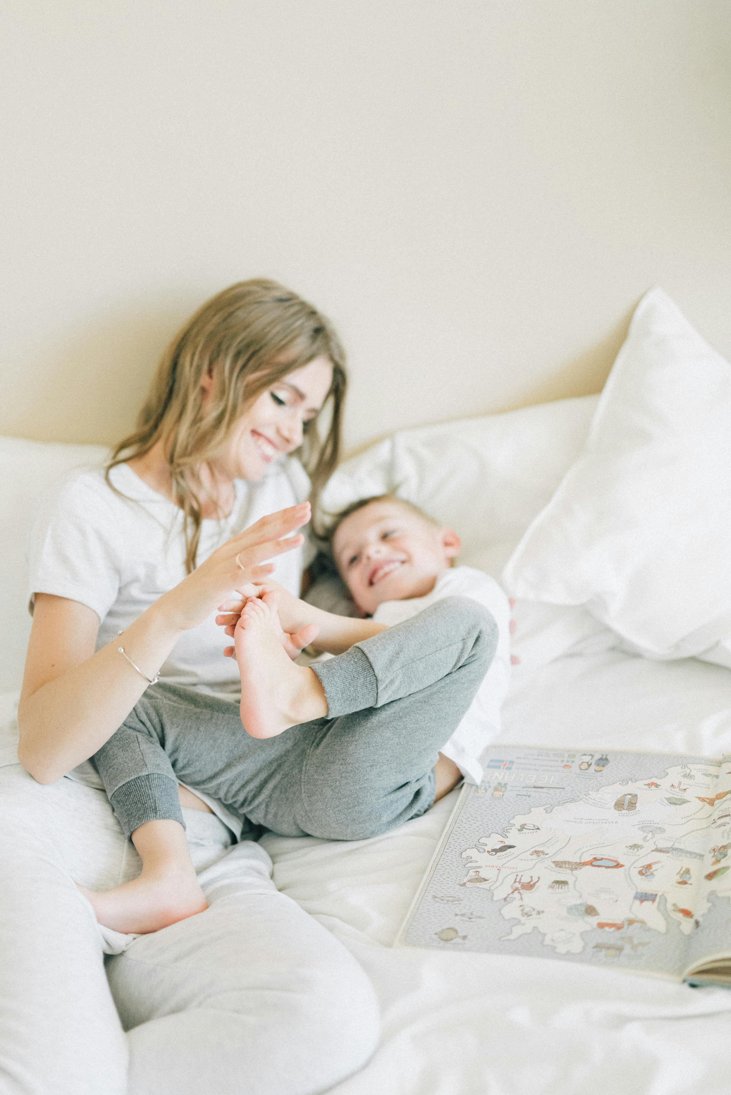 A mother and child share a joyful moment together on a bed, enhancing their bond.