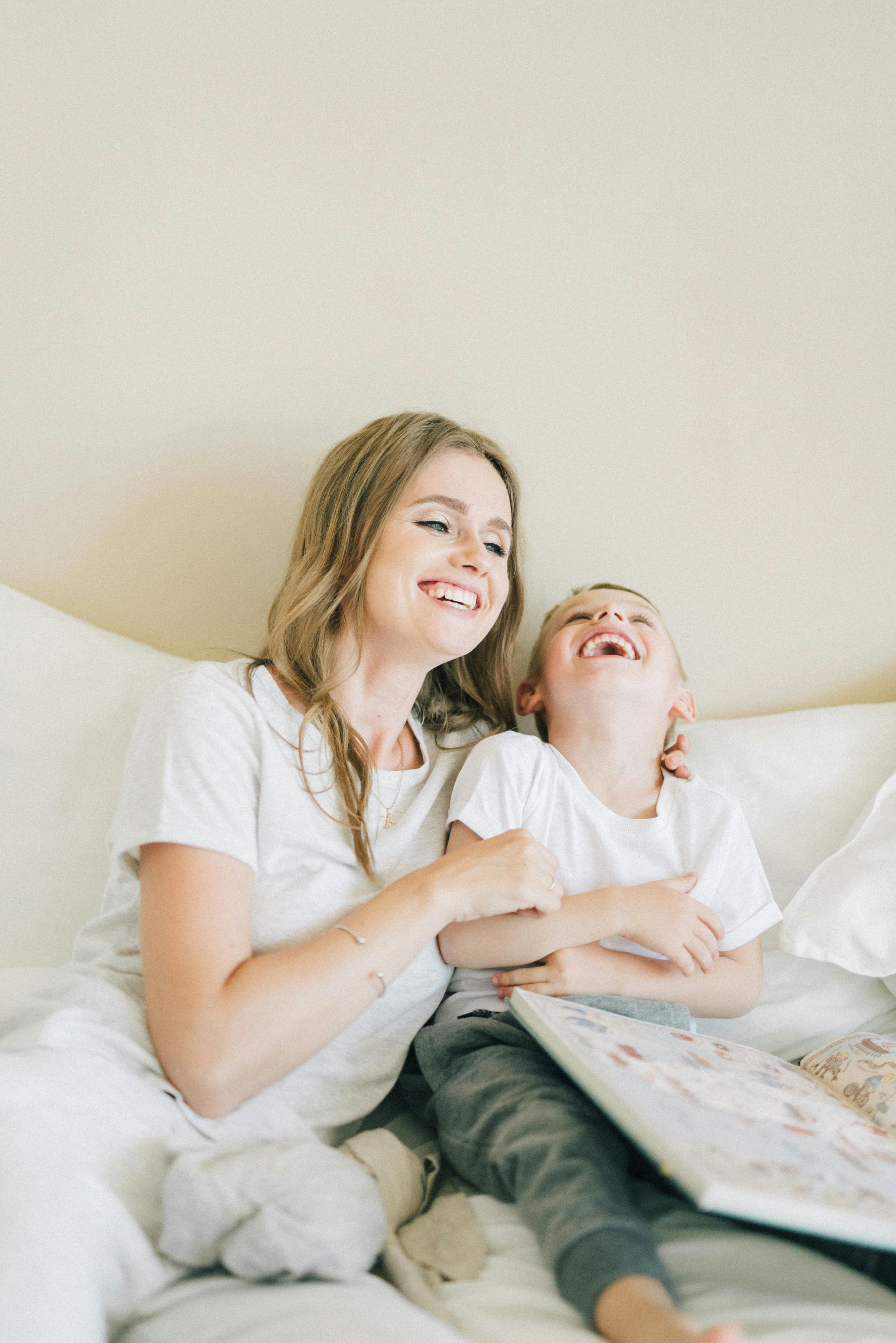 a woman laughing with her son on a bed