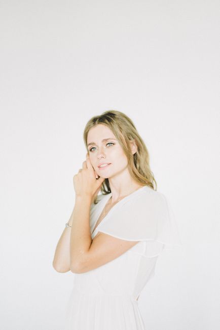 Portrait of an elegant woman posing in a bright, minimalist setting, highlighting beauty and grace.