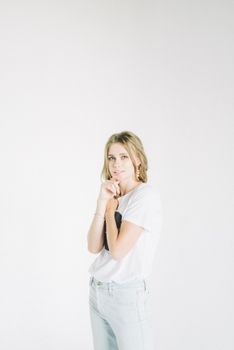 一位休闲时尚的女性，自信地站在白色背景前，肖像简约