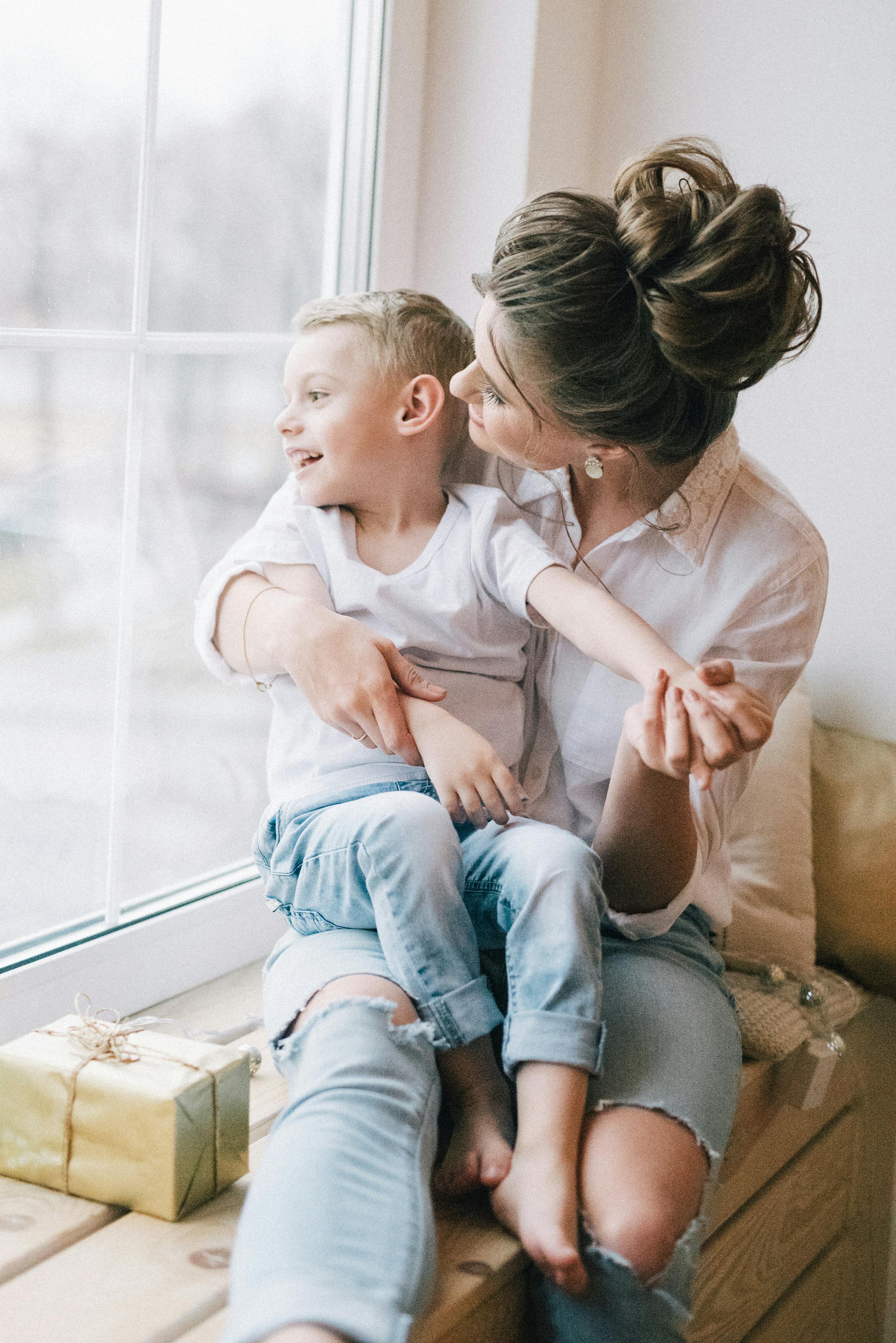 a woman sitting by a window with her son