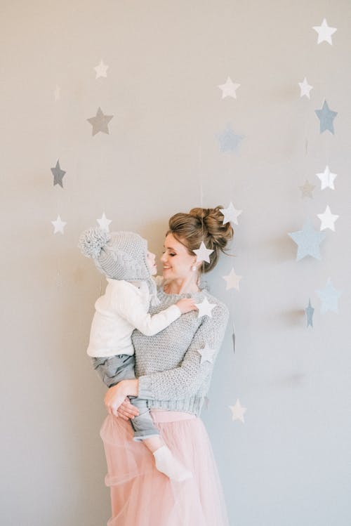 Free Woman In Long Sleeve Shirt Carrying Her Child Stock Photo