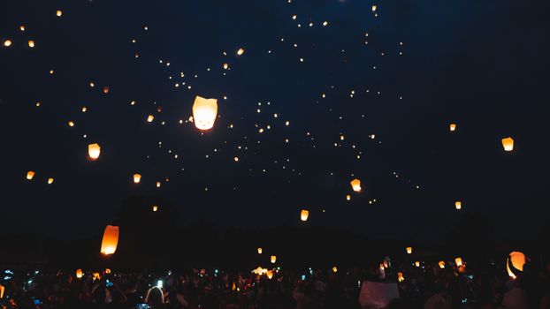 Illuminated sky lanterns floating at a nighttime festival, a breathtaking celebration event.
