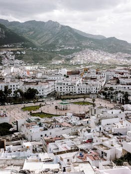 Aerial view of Tetouan cityscape with Rif Mountains in the background under cloudy skies.