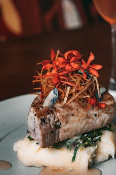 Exquisite gourmet tuna steak on mashed potatoes adorned with vibrant edible flowers.