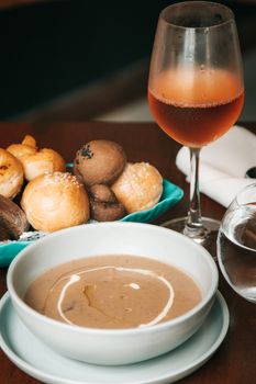 Delicious mushroom soup served with fresh bread and rose wine for a perfect dining experience.