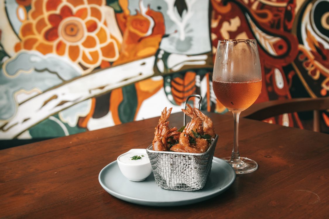 Fried shrimp with sauce on a plate beside a drink