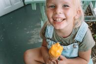 在一个夏天的日子里，一个快乐的孩子坐在室内，享受着美味的冰淇淋蛋卷