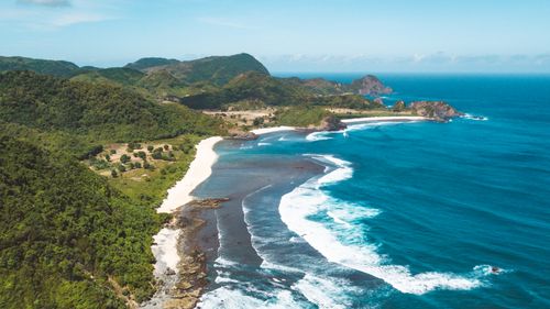 Free A breathtaking aerial view of a serene tropical coastline with lush green hills and pristine blue waters. Stock Photo