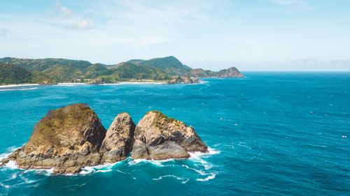Free Aerial view of a breathtaking rocky coastline with turquoise waters under a clear summer sky. Stock Photo