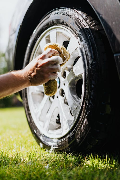 Free Person Holding Sponge Washing Car Tire Stock Photo