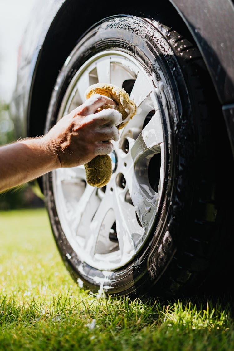 Person Holding Sponge Washing Car Tire