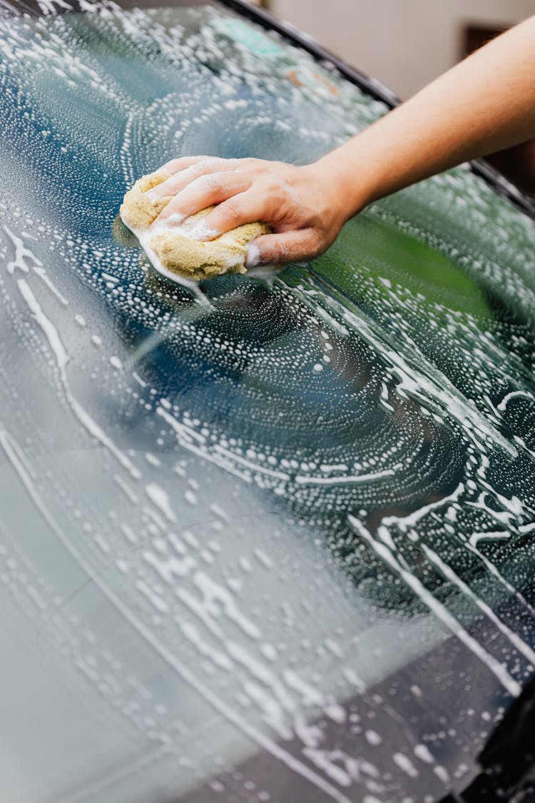 A Person Washing A Car Windshield