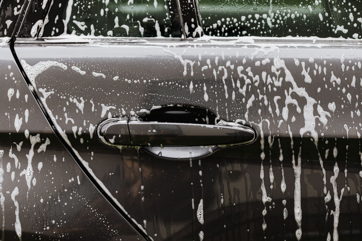 Soap suds on a black car door during a hand wash