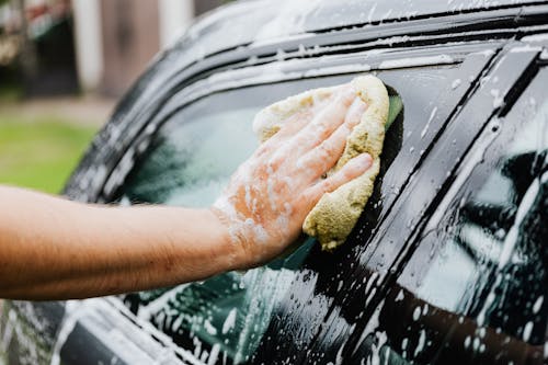 Person Holding a Sponge Washing His Car