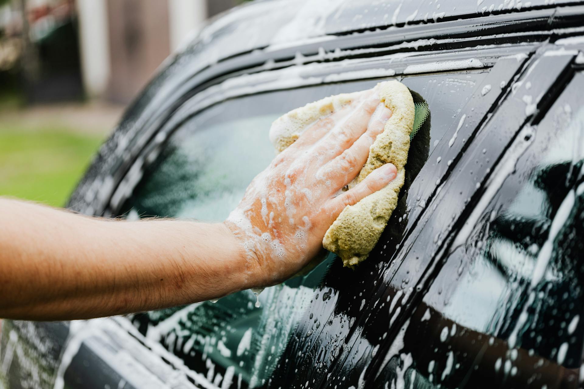 Person Holding a Sponge Washing His Car