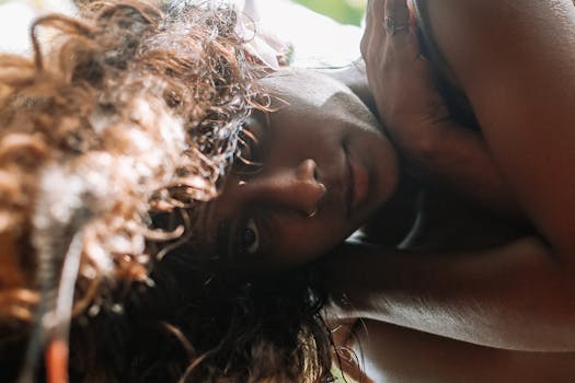 一位卷发女子躺着的亲密特写肖像，若有所思地凝视着