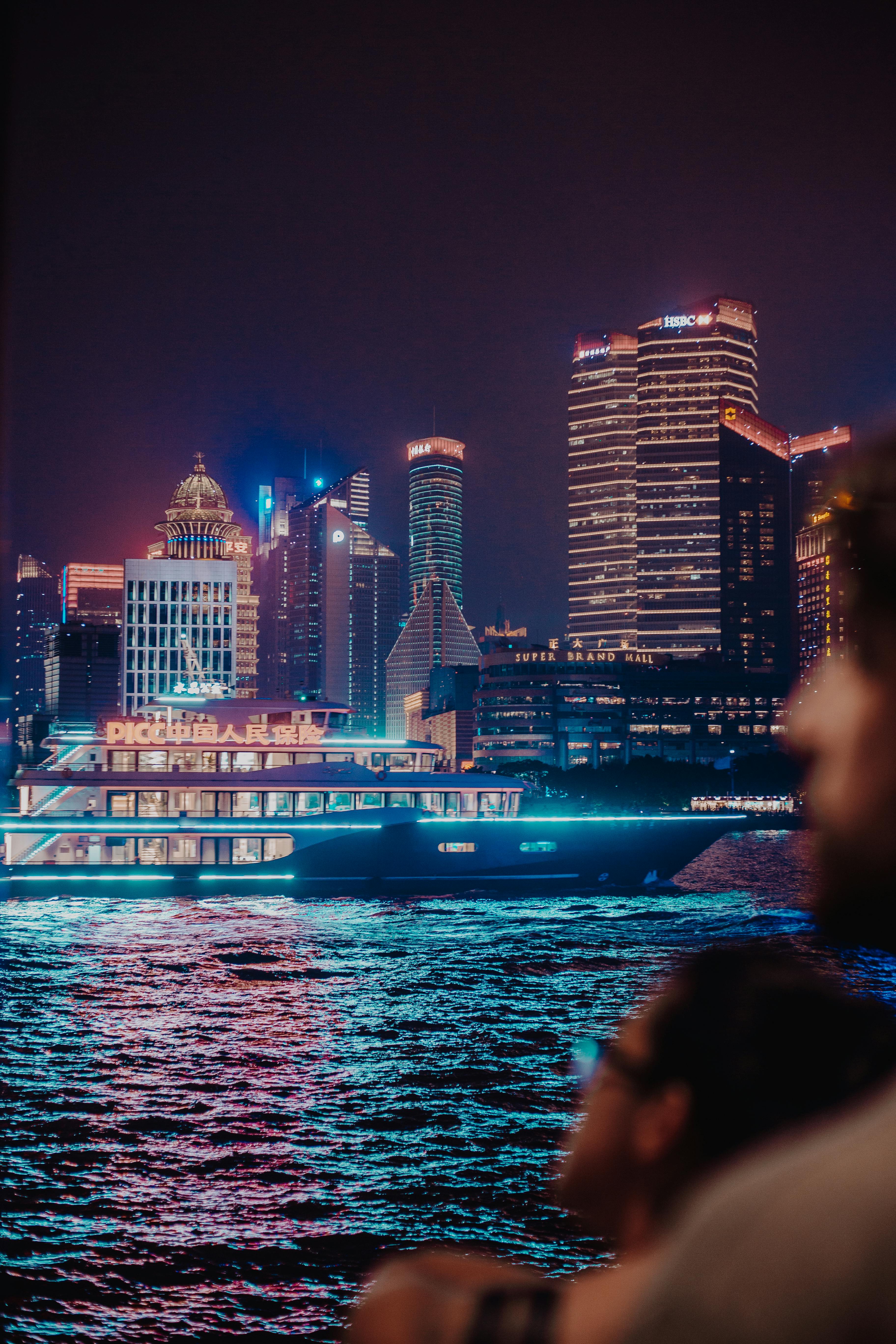 夜晚，游船穿过黄浦江，上海浦东区的天际线被灯光照亮