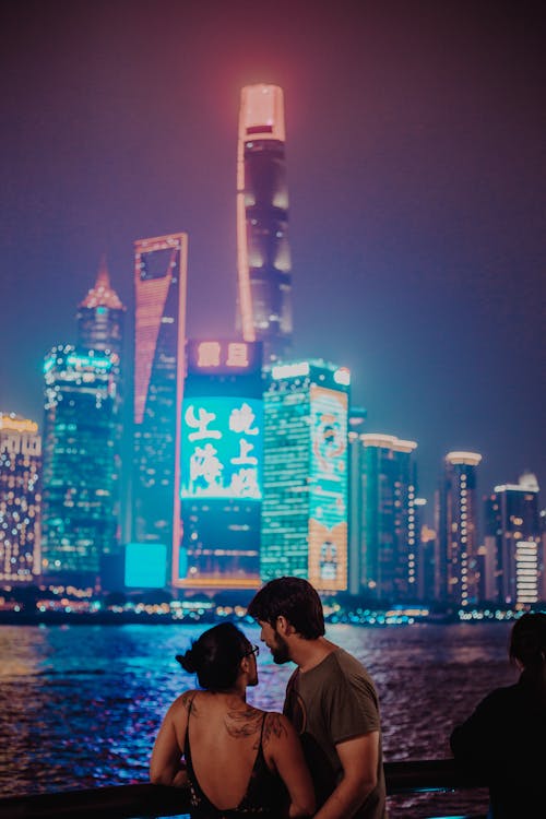 A Couple with a View of Illuminated Buildings at Night