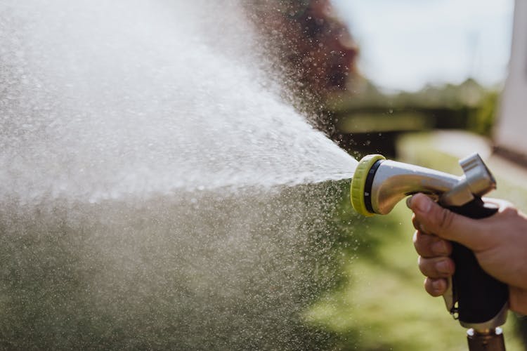 Close-Up Photo Of A Person Using A Spray Hose