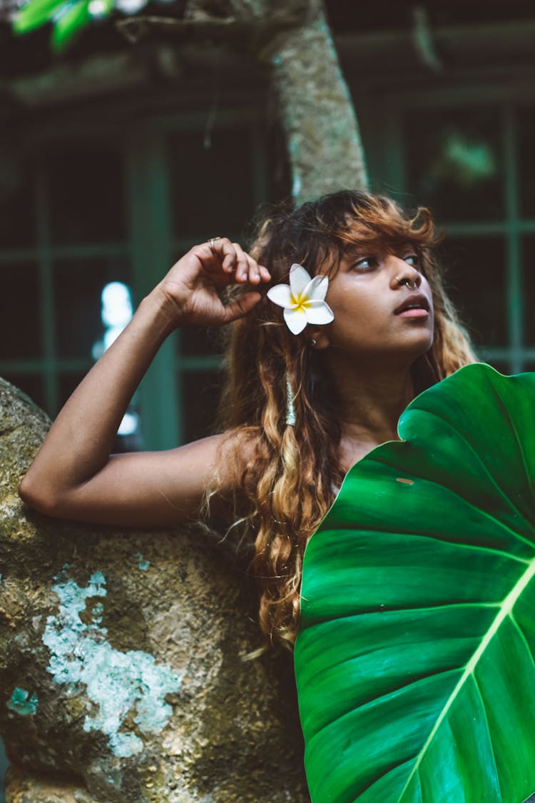 Woman With Flower In Hair Holding Large Leaf