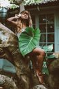 Woman with Huge Leaf Sitting on Tree