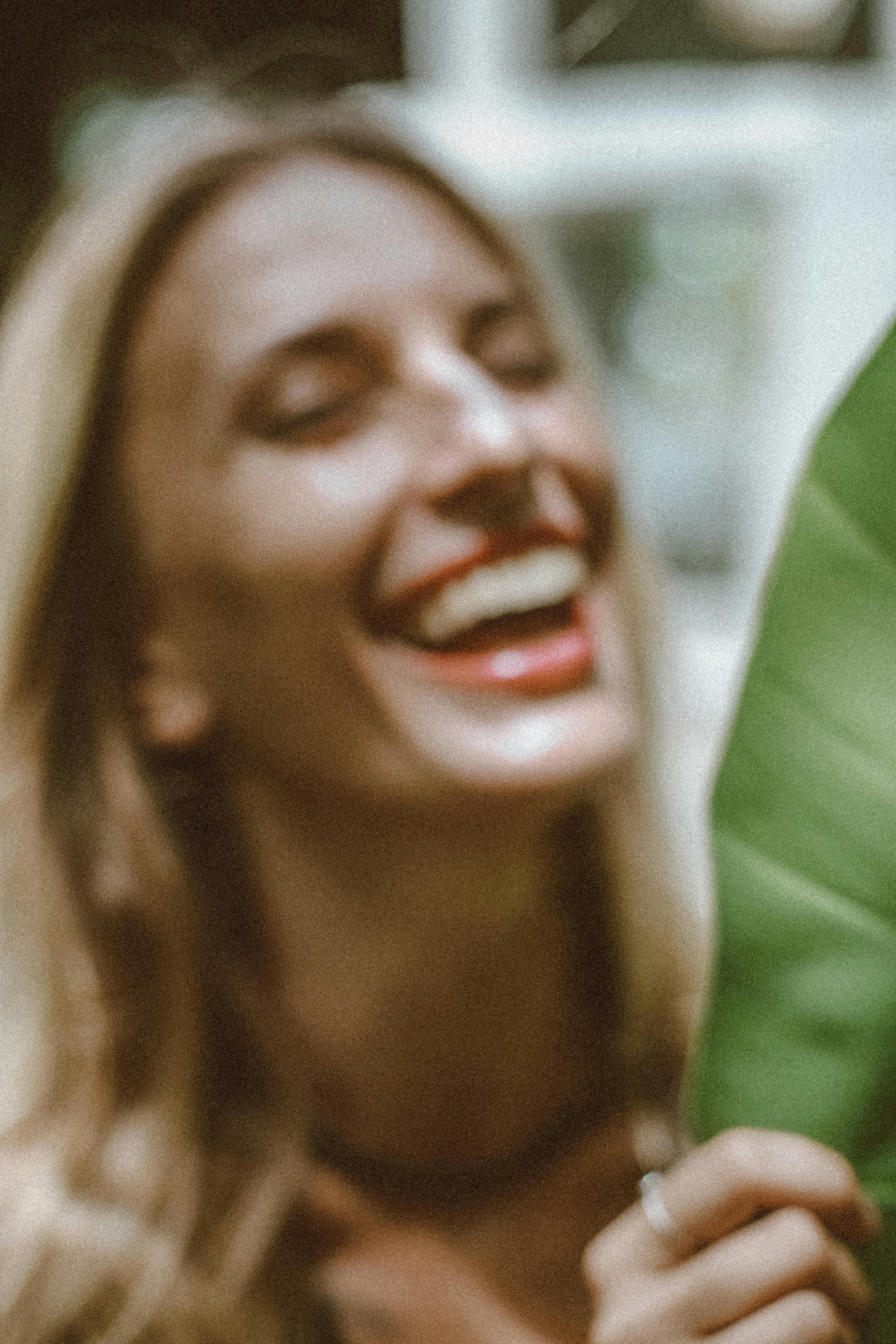 一幅金发女人与叶子一同欢笑的散焦艺术肖像，唤起了欢乐与自然之感
