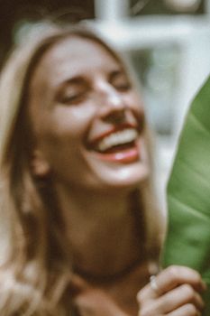 一幅金发女人与叶子一同欢笑的散焦艺术肖像，唤起了欢乐与自然之感
