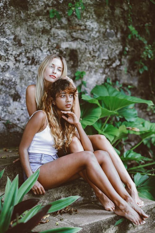 Two Women Sitting Among Lush Foliage 