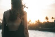 日落时分，一个女人站在岸边，棕榈树为背景，享受着夏日的氛围