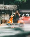 Woman in Black Tank Top and Orange Skirt Sitting on Orange Motor Scooter during Night Time