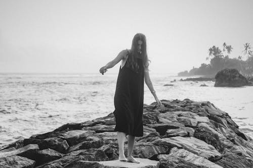 Free Woman Walking Barefoot on Rocks in Seaside Stock Photo