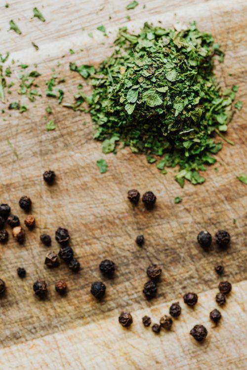 Free Close-up of fresh herbs and peppercorns on a rustic wooden surface. Stock Photo