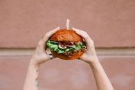 Person Holding Burger With Tomato and Lettuce