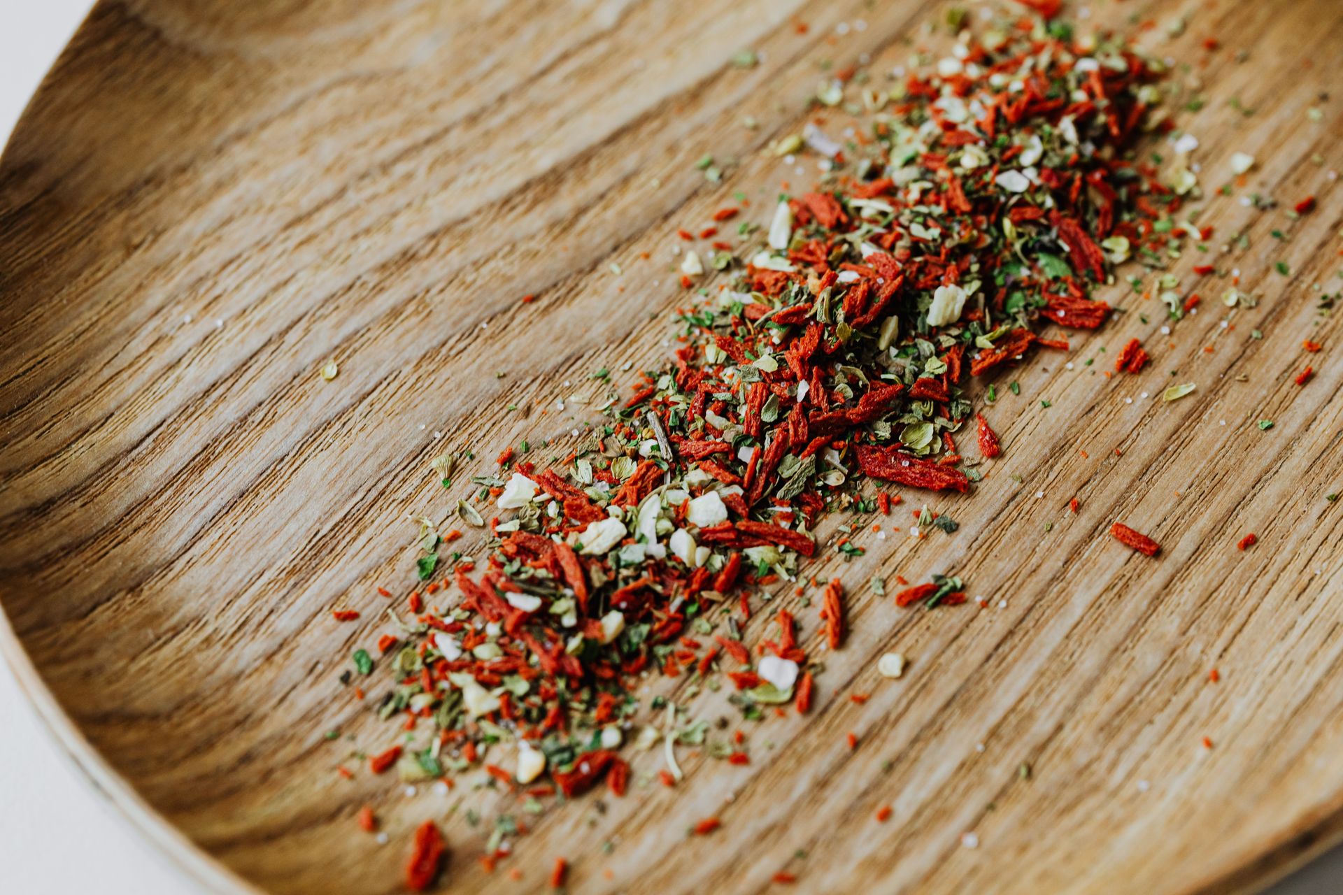 Close-up of vibrant dried herbs and spices scattered on a wooden board.