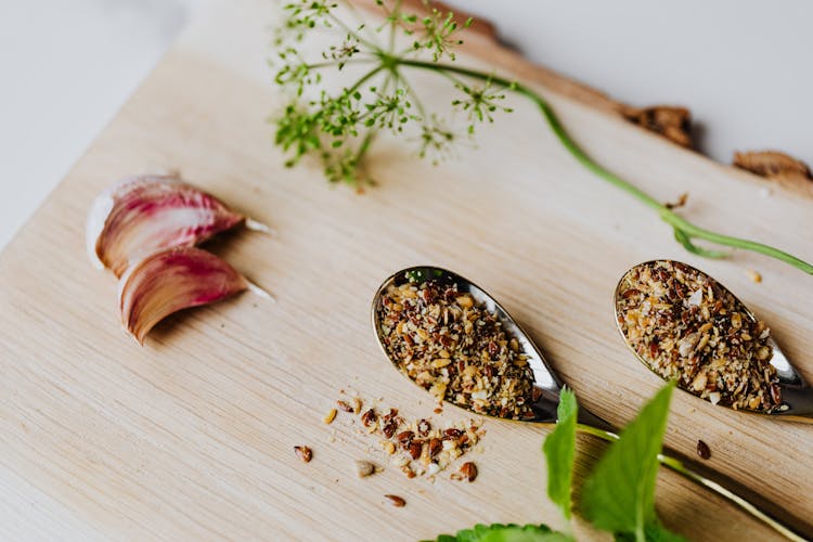 Garlic Cloves, Spices, And Herbs On Stainless Spoons