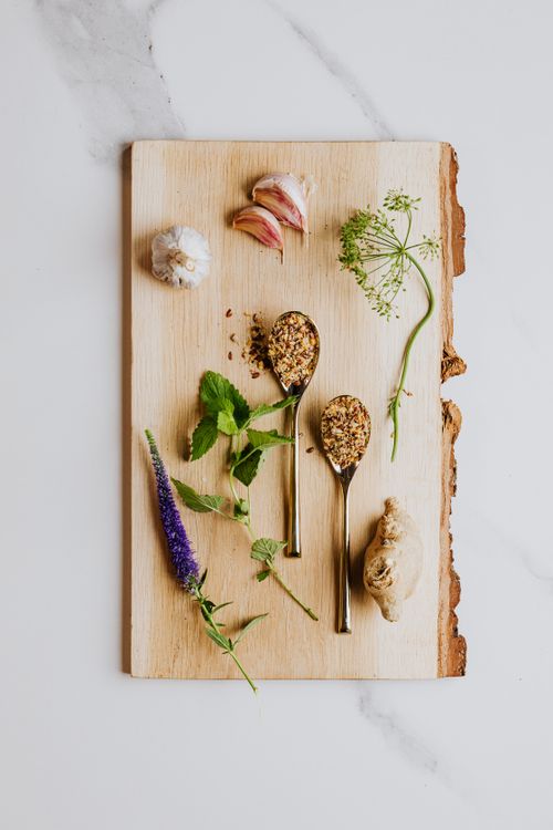 Free Flat lay of assorted spices, herbs, garlic, and ginger on a wooden board for culinary use. Stock Photo