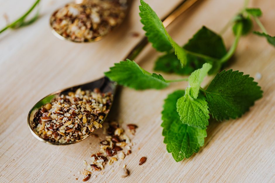 Mint leaves and mixed spices in spoons on a wooden surface, perfect for culinary enthusiasts.