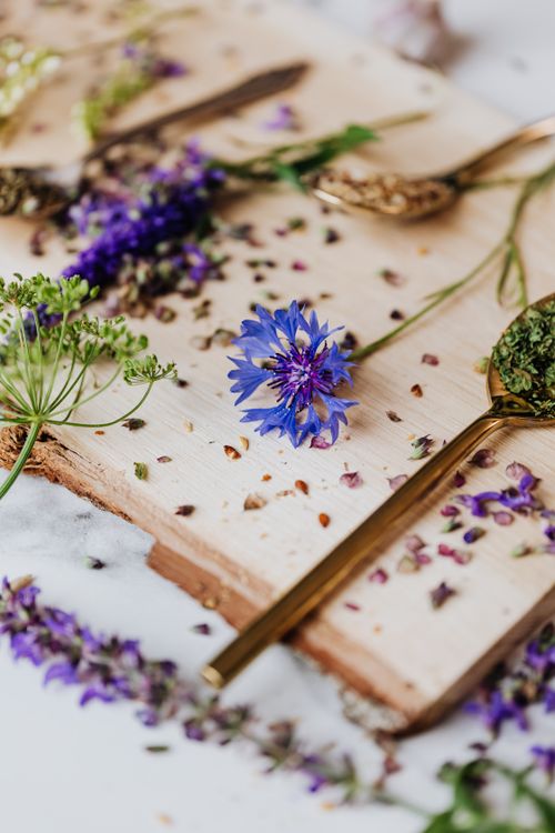 Free Close-up of fresh herbs and flowers with golden teaspoons on a wooden board. Stock Photo