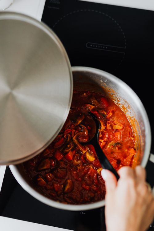 Free Close-up of shakshuka cooking in pot with spoon stirring. Perfect for culinary enthusiasts. Stock Photo